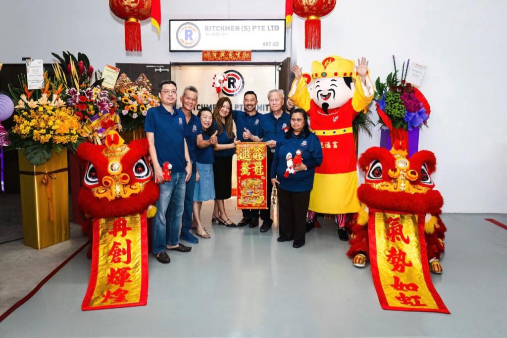 The Ritchmen team photographed with the lion dance troupe and God of Fortune at the company entrance.