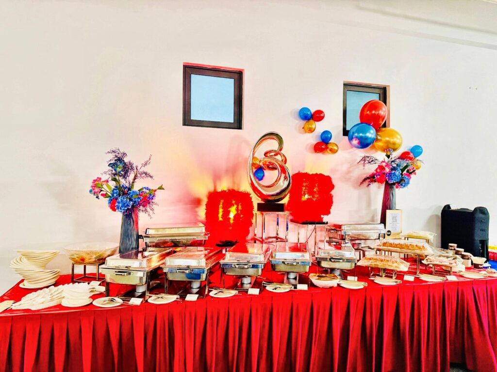 Buffet table with chafing dishes, flowers and balloons set up for the Ritchmen 50th anniversary lunch.